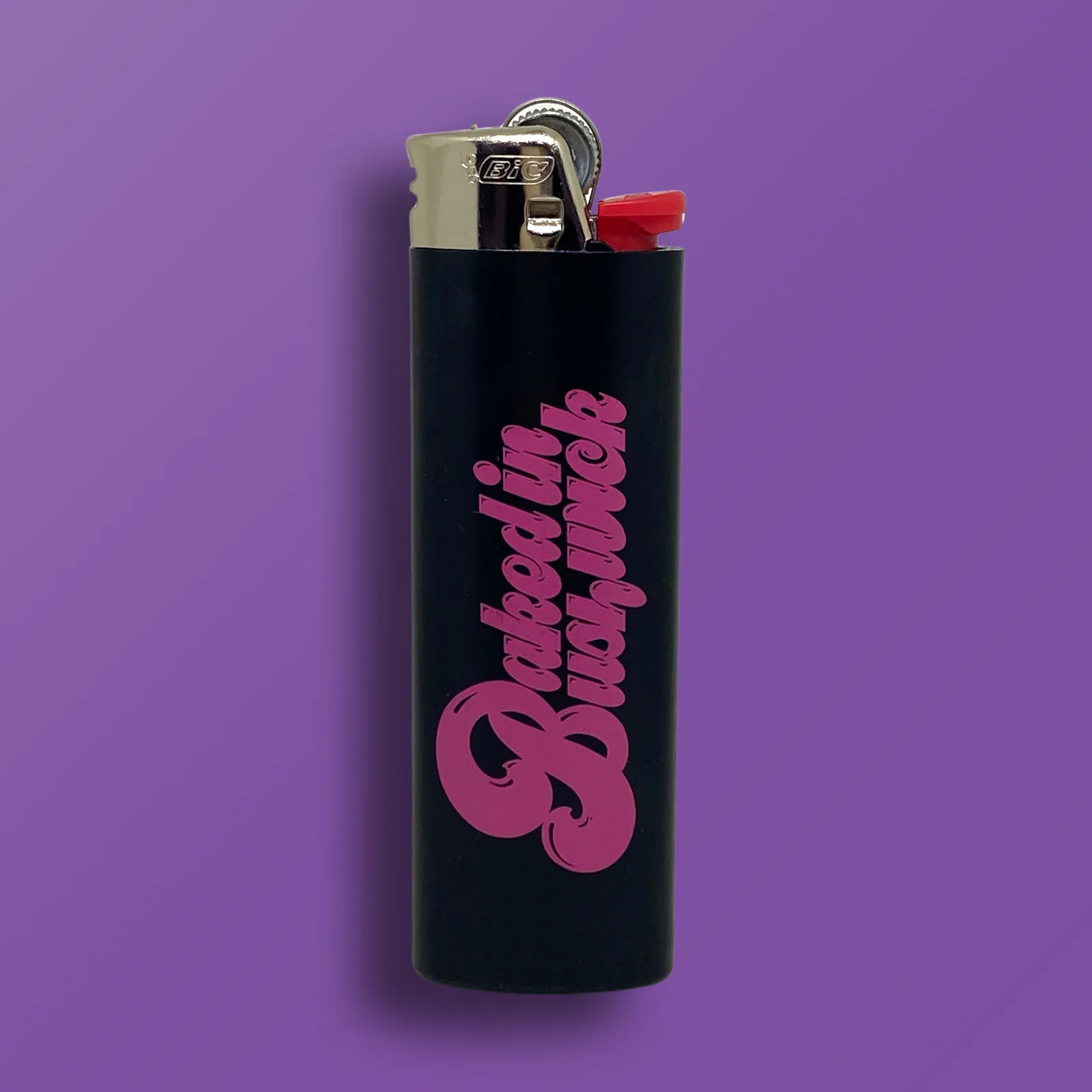Black BIC Maxi lighter with hot pink Baked In Bushwick logo printed on one side, custom cannabis accessory