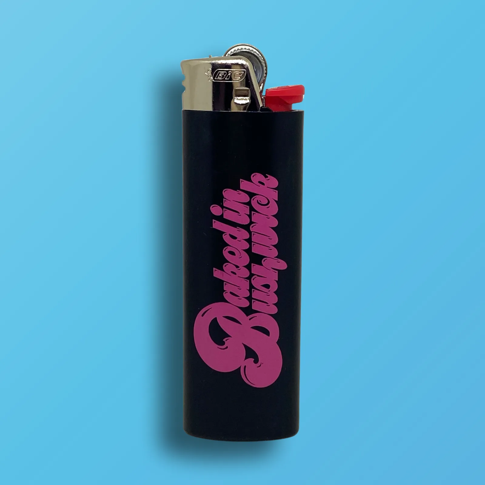 Black BIC Maxi lighter with hot pink Baked In Bushwick logo printed on one side, custom cannabis accessory